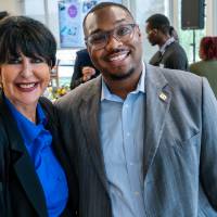 President Mantella standing with event guest, both smiling at camera